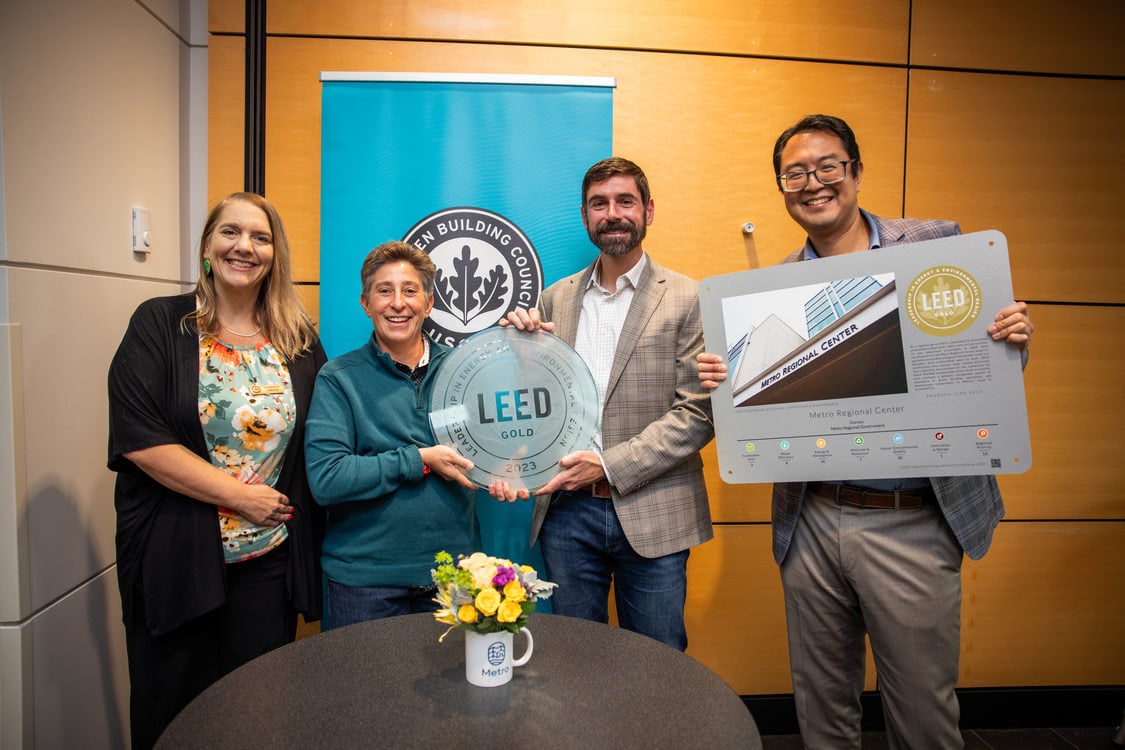 Metro Councilor Duncan Hwang and other Metro staff members hold the LEED Gold plaque and certification poster in the council chamber of Metro Regional Center.