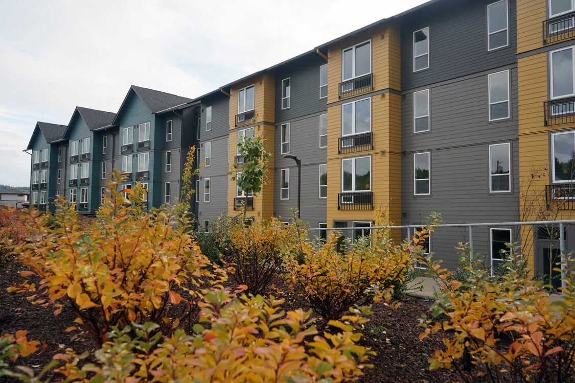 Four story apartment building with shrubbery in the foreground