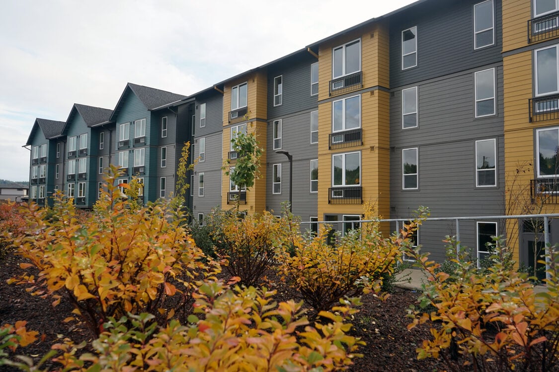 Four story apartment building with shrubery in the foreground