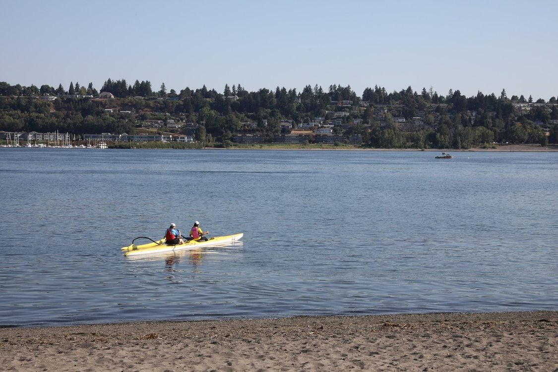 two people in a kayak paddle out from the shore of the Columbia River at Broughton Beach