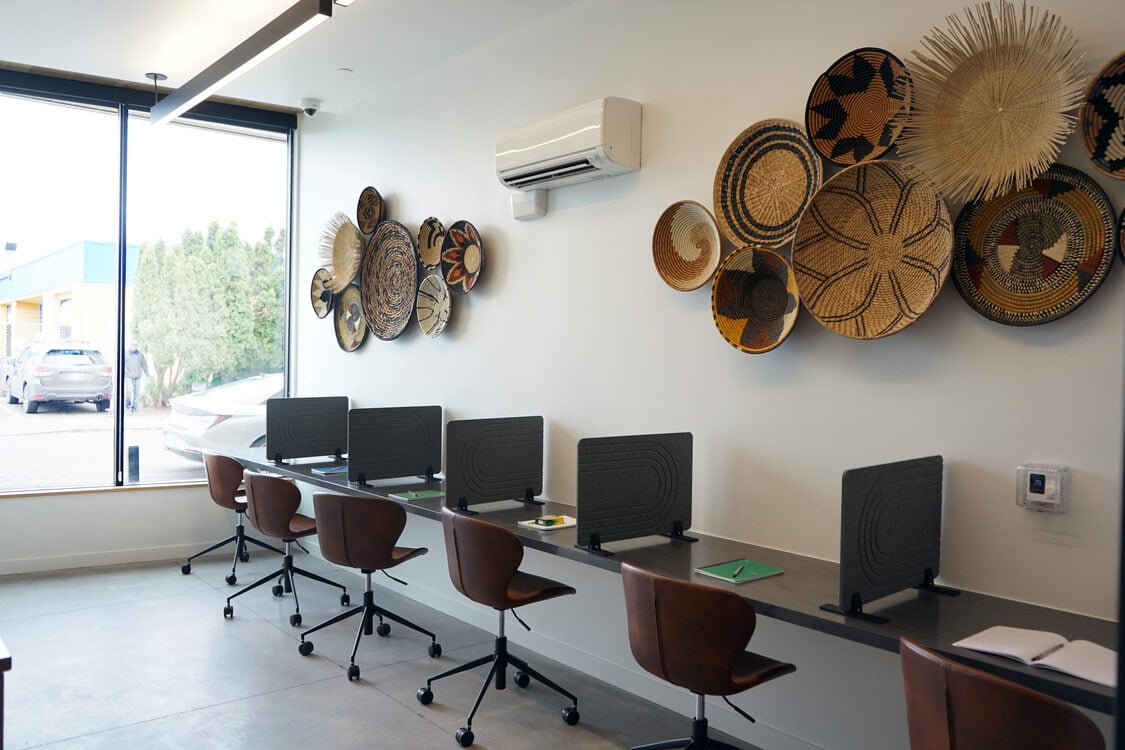 Room with long countertop and chairs, with partitions along the counter to create individual work stations. 