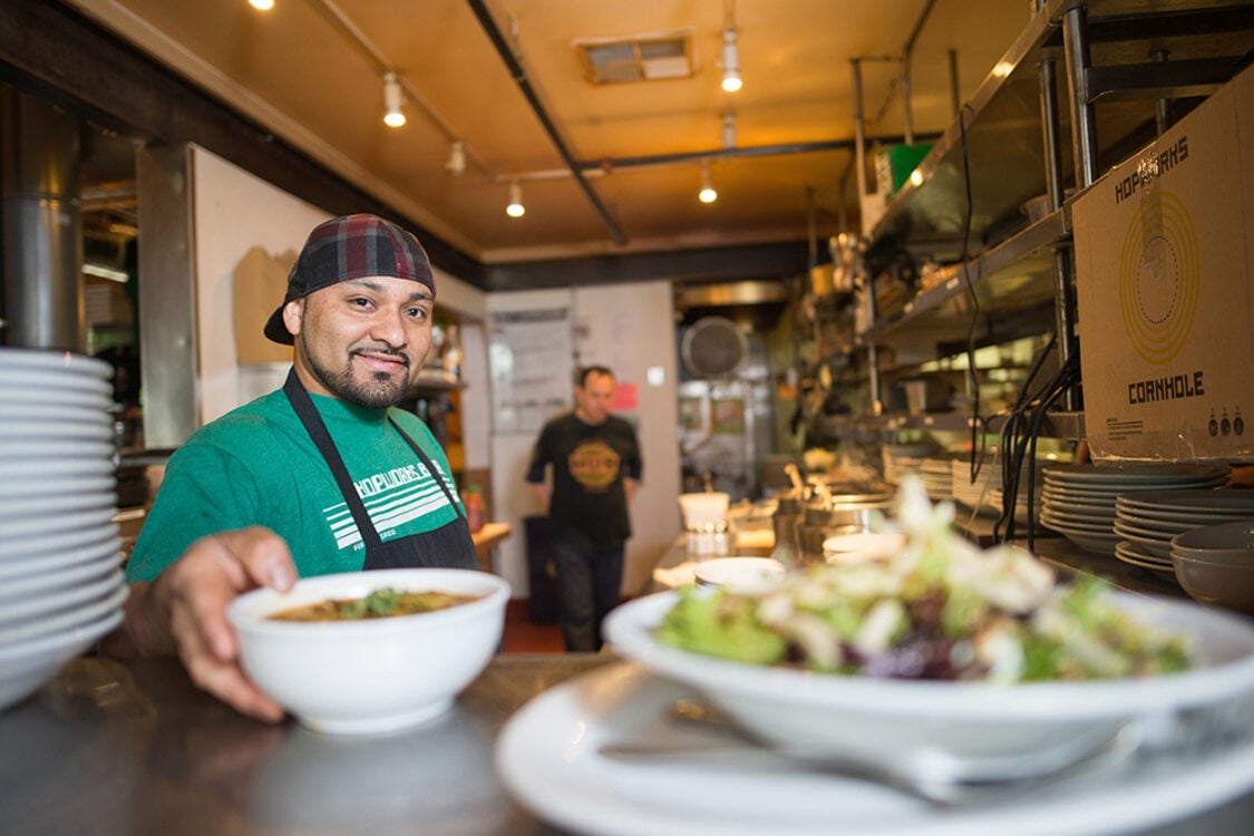Interior of a restaurant countertop with staff putting food on a stainless steel counter
