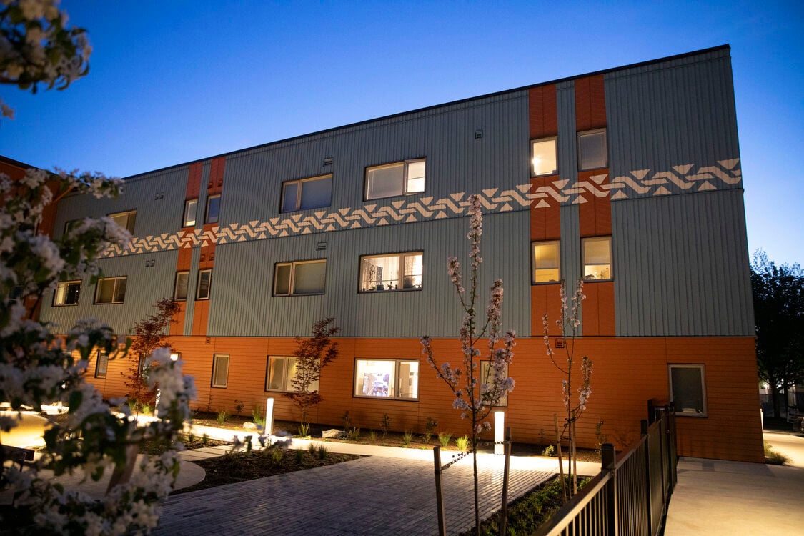 Three storey apartment building with a central courtyard at twilight. 