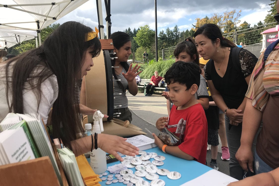 Metro staff explain cleaning products and provide information to a family at a healthy homes booth