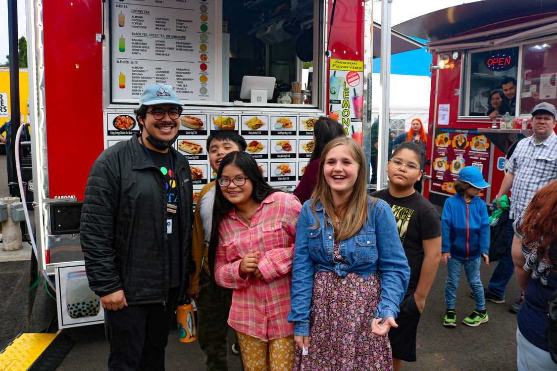 A group of youth pose for a photo in front of a food cart at The Yard at Montavilla food cart pod