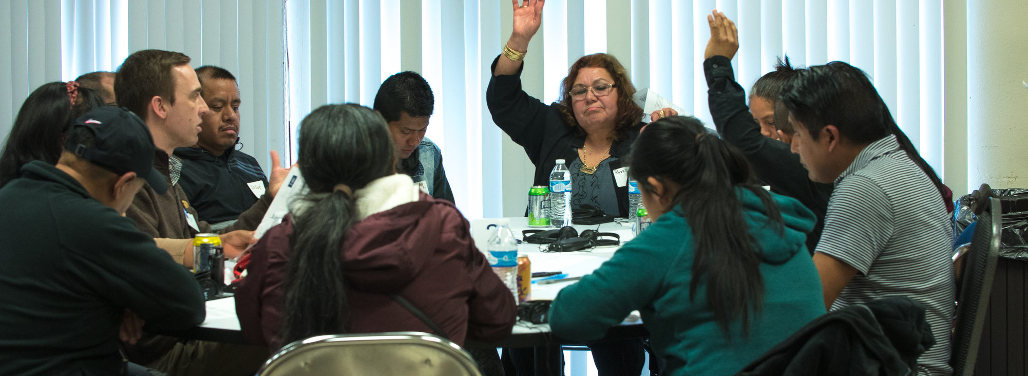 people raise their hands to vote on topics during a roundtable discussion at a community workshop