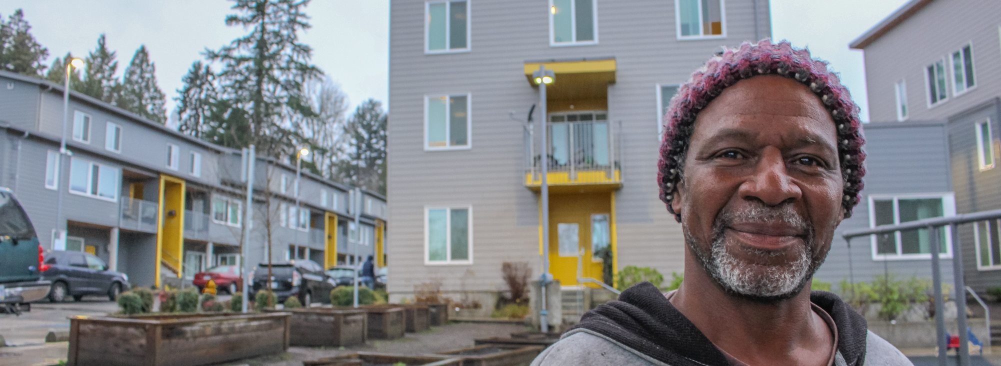 A man stands in the playground and garden common areas of a housing complex