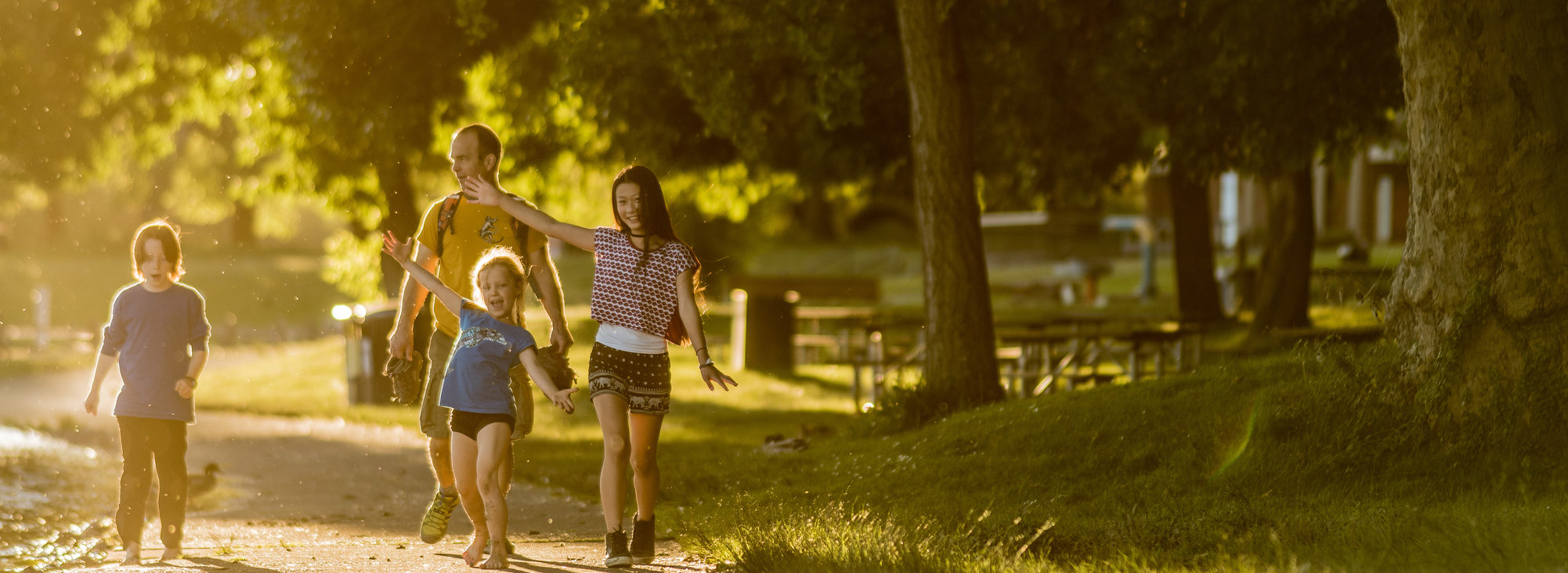 A family of four, one adult and three kids, walks along the path at Blue Lake Park