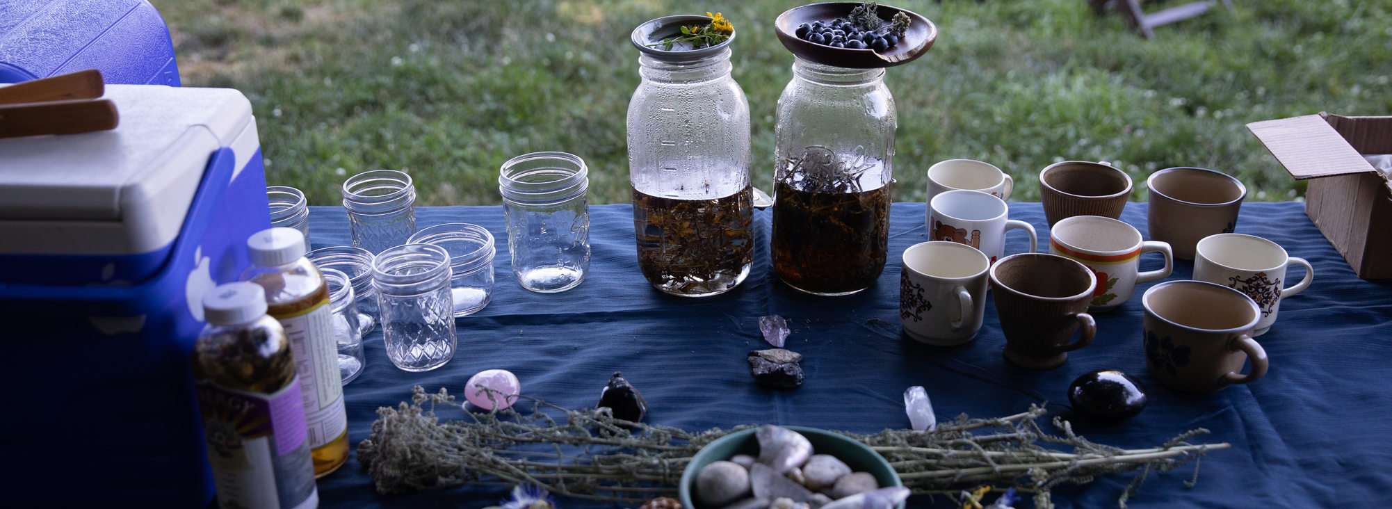 Atabey Medicine table with a blue table cloth and mason jars, plants, and stones