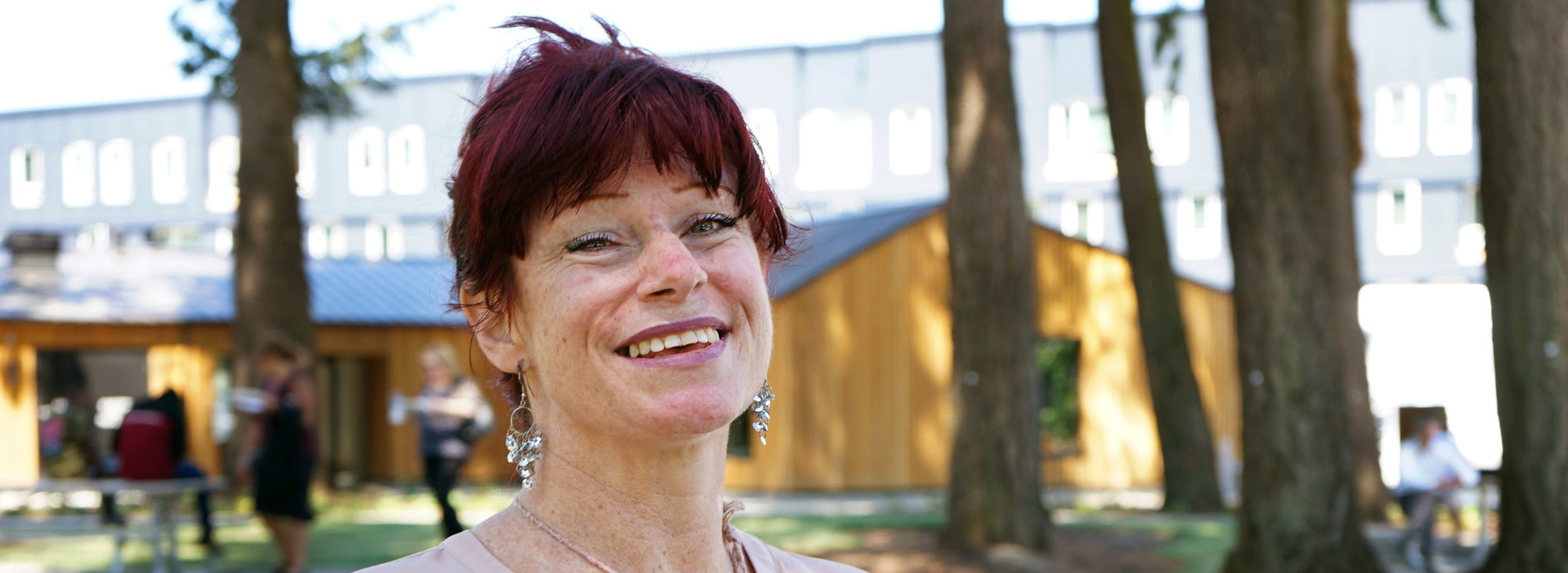 Close up of a woman with red hair, smiling in front of an apartment building