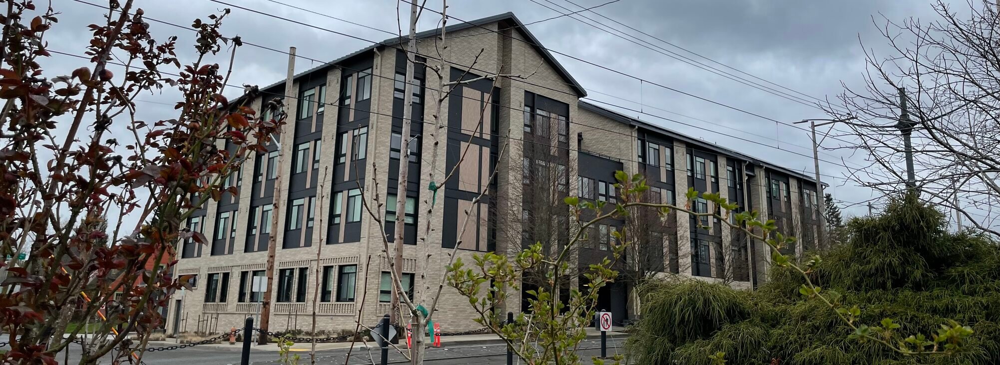 Four story apartment building with shrubbery in the foreground