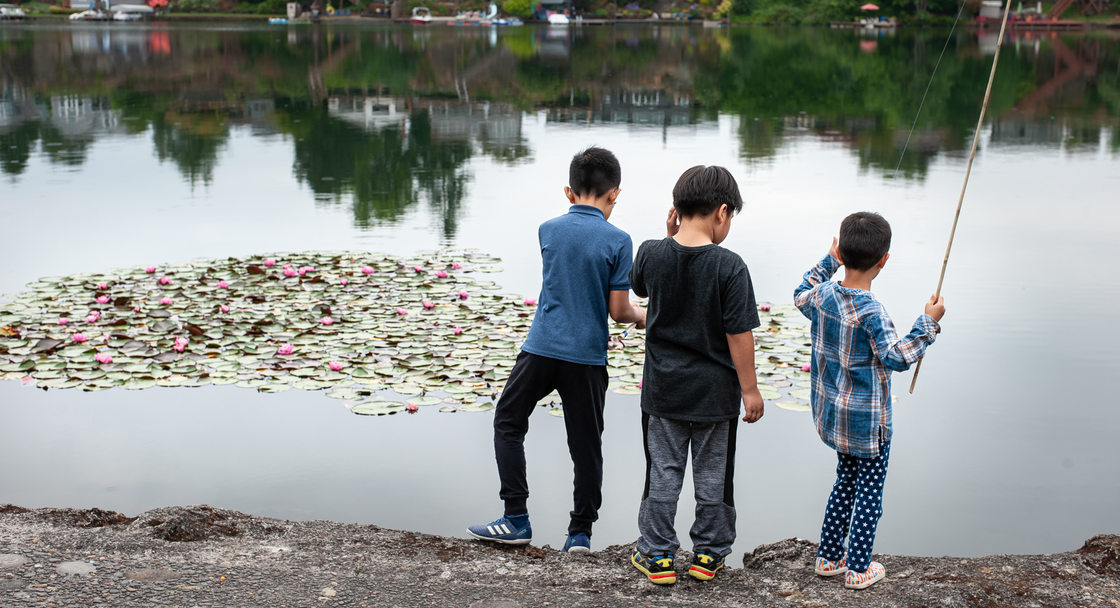 Three kids fishing from the shoreline at Blue Lake Park
