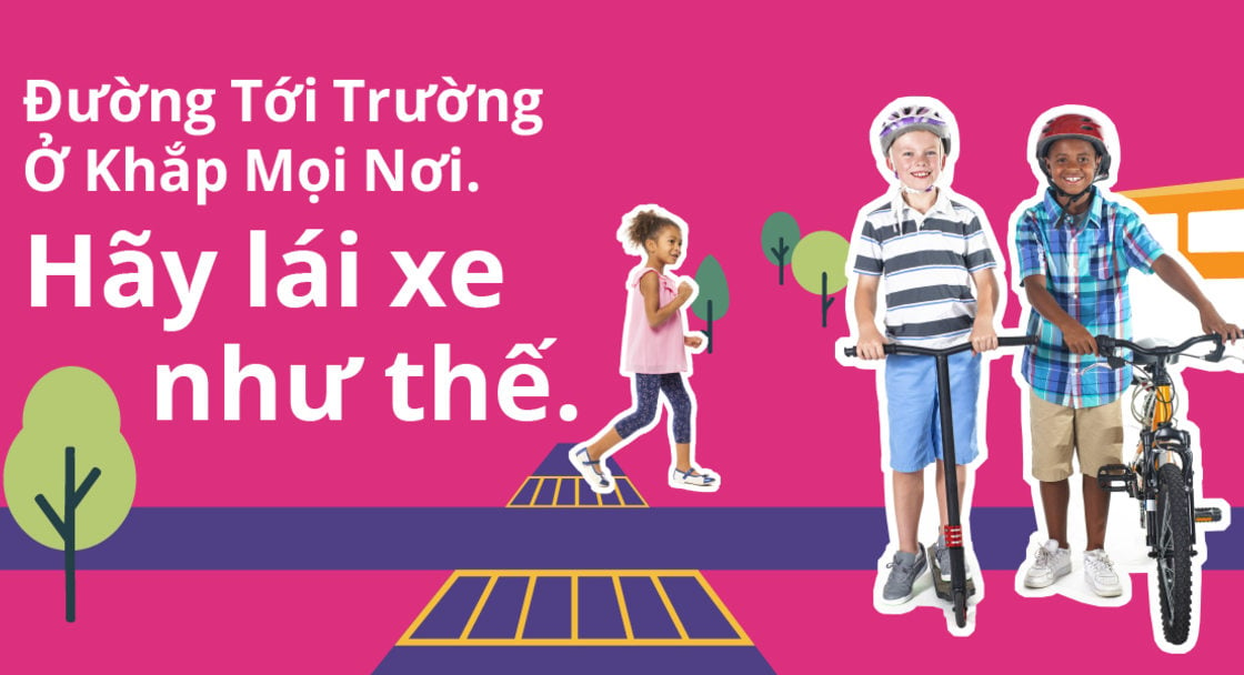 Safety campaign poster with text saying "School routes are everywhere. Drive like it" in Vietnamese. Two children are standing with bikes and scooters with an animated background