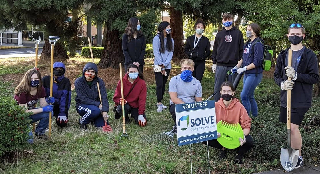An image of volunteers with garden tools standing behind a SOLVE sign