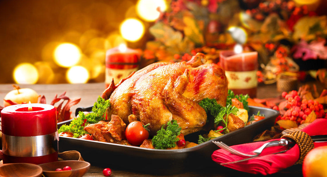 Image of a holiday dinner table featuring a roasted turkey and candles