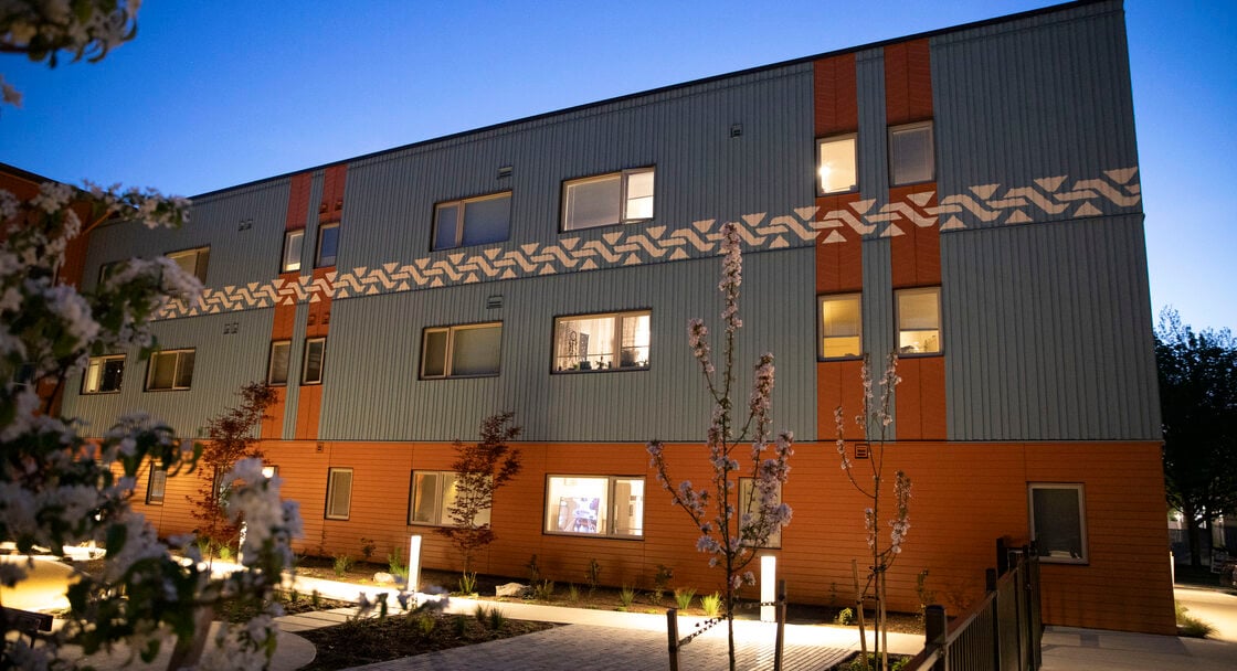 Three storey apartment building with a central courtyard at twilight. 
