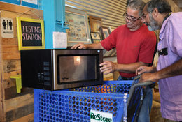 two men look at and test out a used microwave 