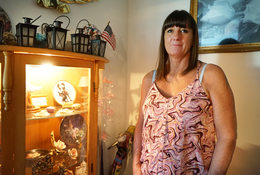 Woman in pink blouse standing by cabinet with small decorative objects